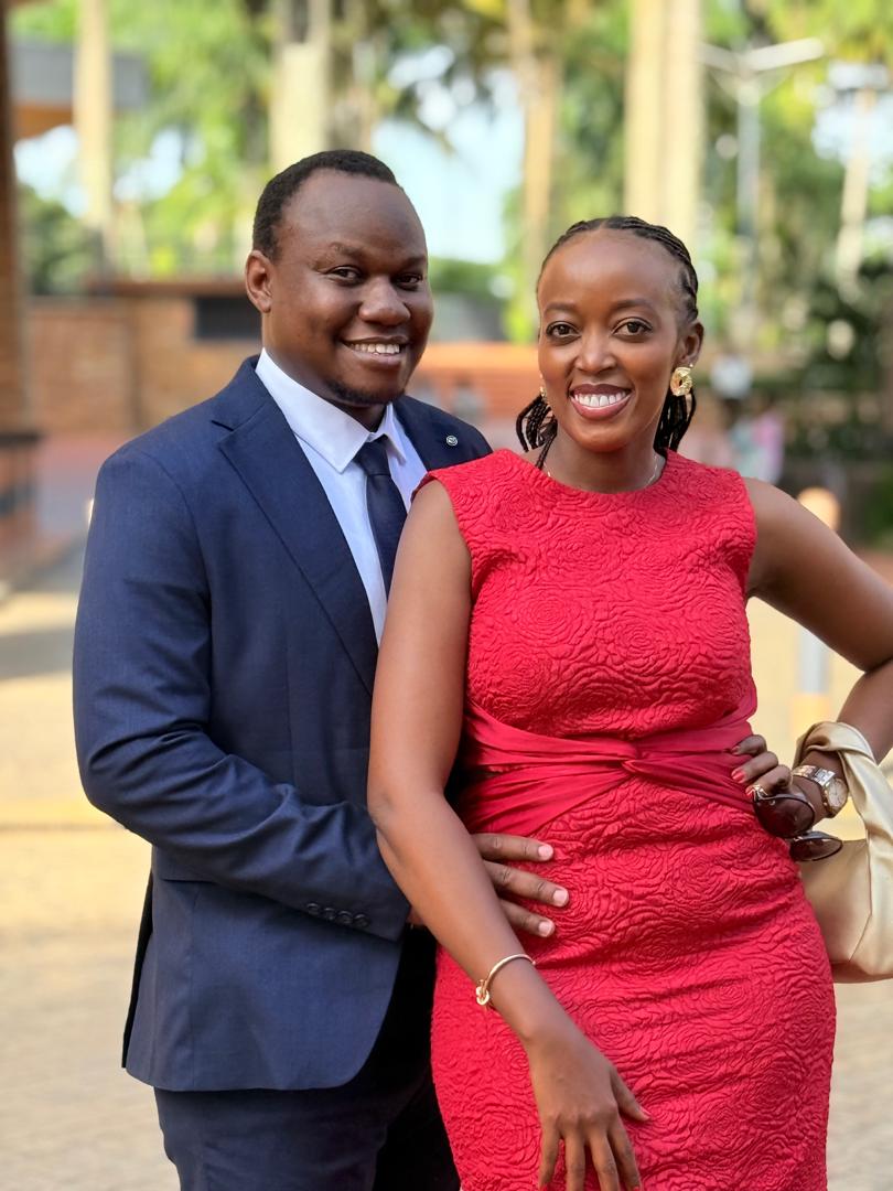 Brian in a navy suit and Angella in a red dress, dressed up and smiling